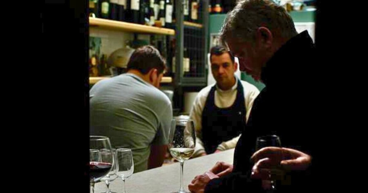 Guests and staff interacting at the Cinque Wine & Deli bar during an intimate wine service moment, highlighting hands-on learning and hospitality experience.