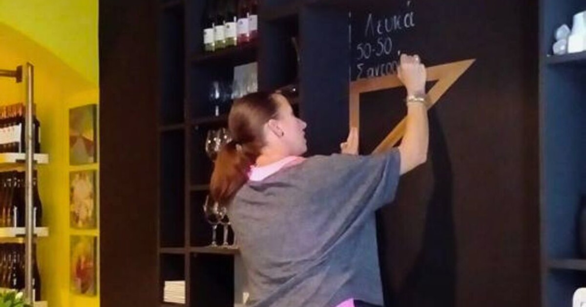 Team member preparing the chalkboard wine list at Cinque Wine & Deli, showcasing wines by the glass during the early days of the wine bar in Athens.