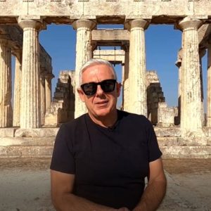 Man standing in front of an ancient Greek monument, symbolizing cultural authenticity and meaningful travel experiences in Greece.