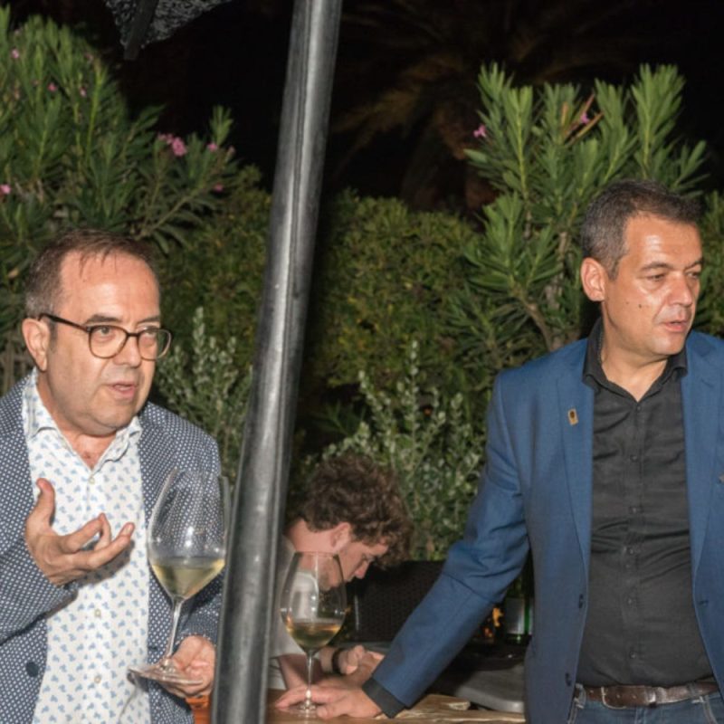 Dr I Voyatzis and Nikitas Prassas presenting Santorini wines at Cinque Wine & Deli Mykonos during a sunset wine tasting event.