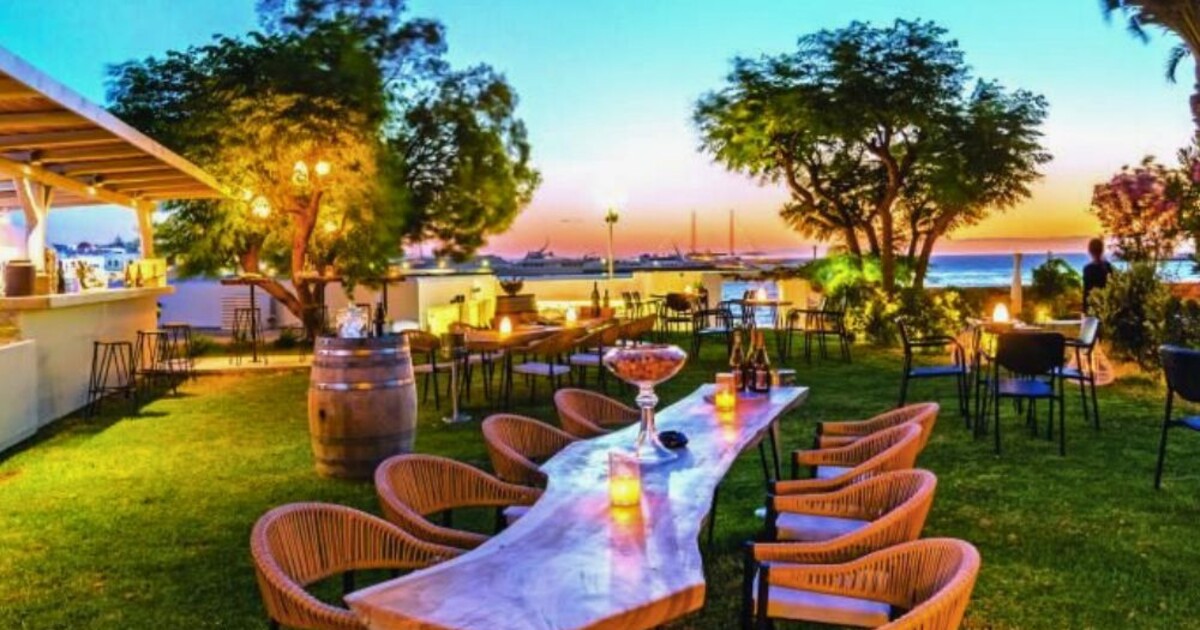 Outdoor garden setting at Cinque Mykonos during sunset, featuring tables set for wine and social gatherings in a seasonal Mediterranean atmosphere.