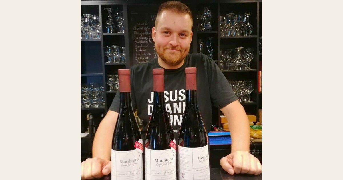 Nikitas Prassas holding Cinque Wine & Deli labeled bottles created for the “A Wine for a Scholarship” initiative supporting the American Farm School of Thessaloniki.