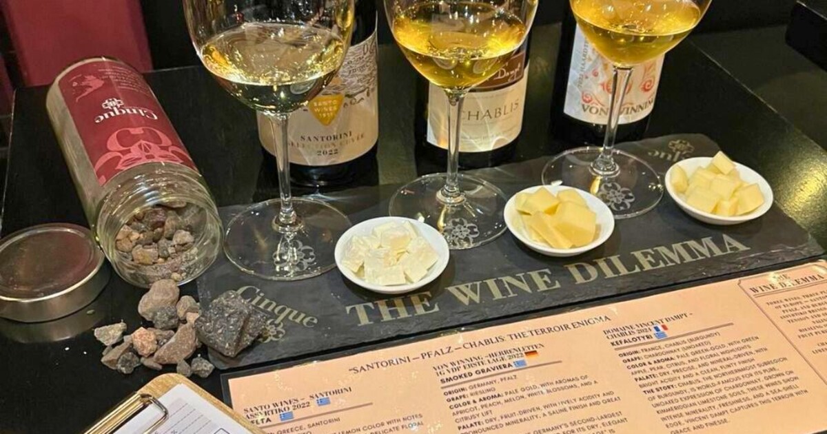 Wine and cheese tasting with three wines and Greek cheeses presented on a stone platter at Cinque Wine & Deli