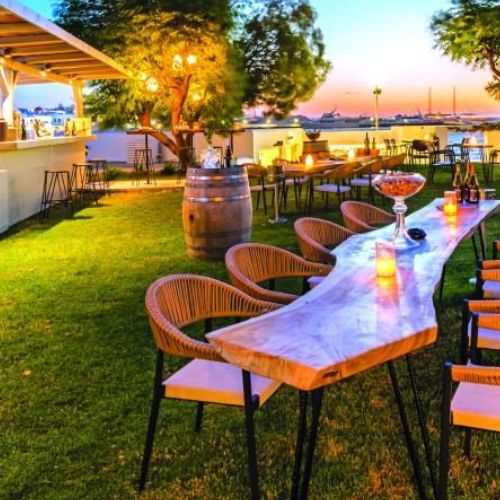Outdoor Cinque Island wine bar setup at a seaside or island destination during sunset.
