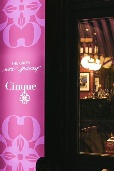 Guests socializing outside a Cinque Wine & Deli wine bar during evening hours.