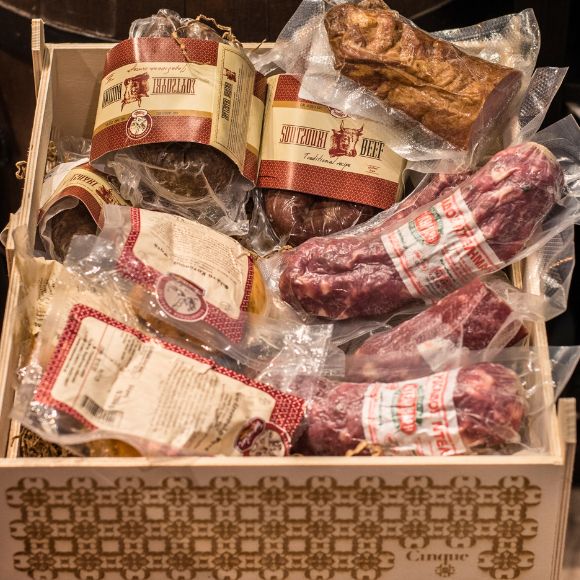 Traditional Greek cured meats and charcuterie arranged in a wooden gift box