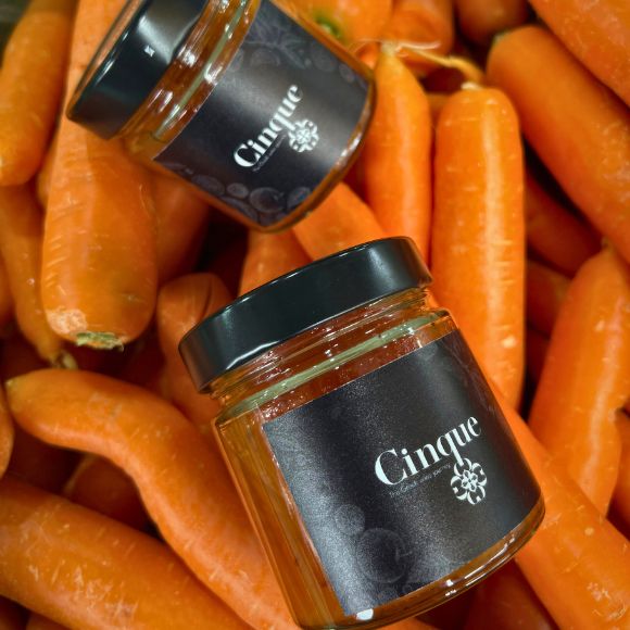 Handmade Greek chutney jars placed among fresh carrots