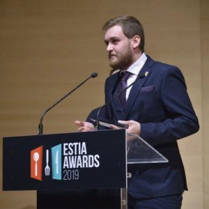 Nikitas Prassas speaking at the ESTIA Awards 2019 podium after receiving the Silver Award for Total Experience for Cinque Wine & Deli in Athens.