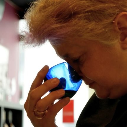 Participant smelling olive oil in a professional tasting glass during a Greek extra virgin olive oil masterclass at Cinque Wine & Deli Athens.