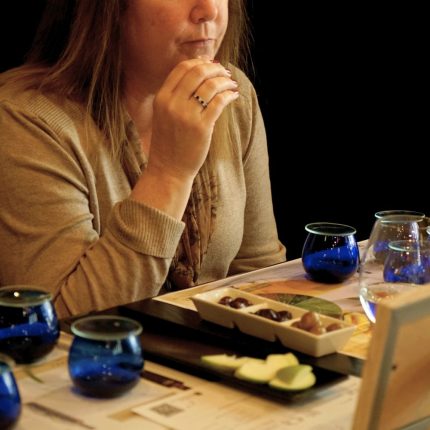 Guest tasting Greek extra virgin olive oil using professional blue tasting glasses at Cinque Wine & Deli