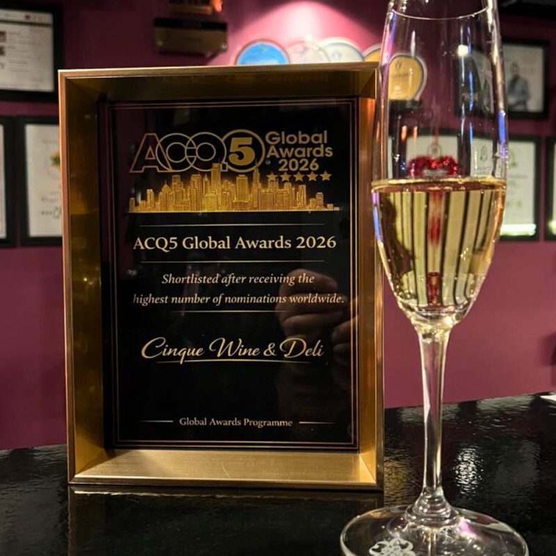 Πλακέτα της shortlist ACQ5 Global Awards 2026 για το Cinque, δίπλα σε ποτήρι αφρώδους κρασιού.