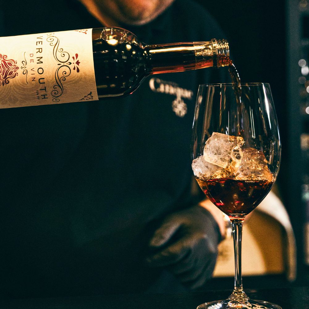 Sommelier pouring vermouth over ice into a wine glass during professional wine list consulting and hospitality advisory service.