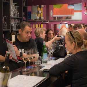 Sommelier presenting Greek bottled wine during a private wine tasting at Cinque Wine & Deli in Athens.