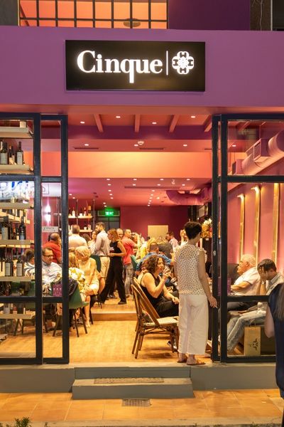 Exterior view of Cinque Wine & Deli Glyfada with guests enjoying wine and food inside.