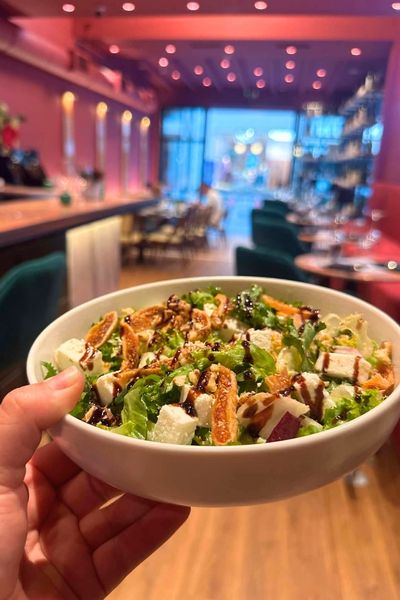 Fresh salad bowl served inside Cinque Wine & Deli Glyfada, with the wine bar interior in the background.