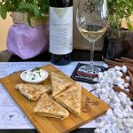 Handmade Greek spinach pie served on a wooden board with Savatiano white wine at Cinque Athens.