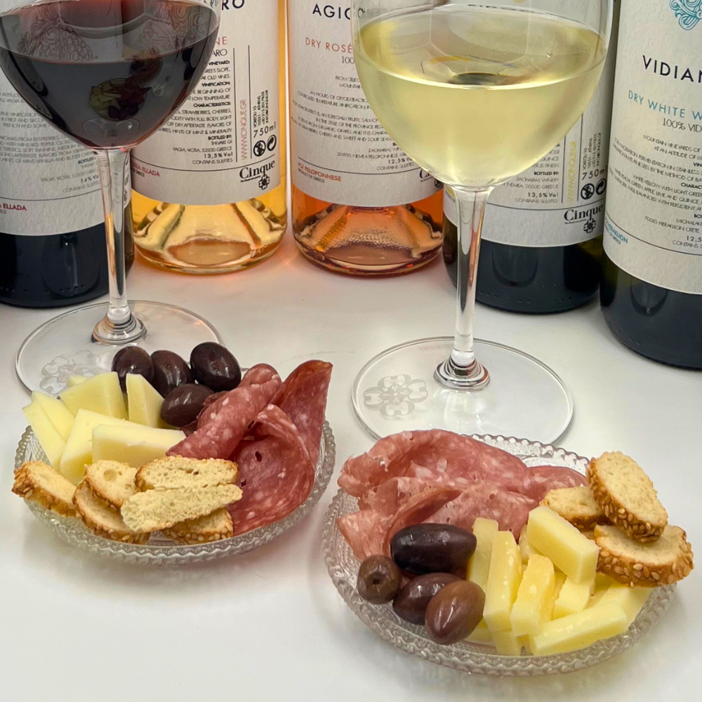 Glasses of white and red Cinque Selection wine with small plates of cheese, cured meats, olives and rusks for Aperivino.