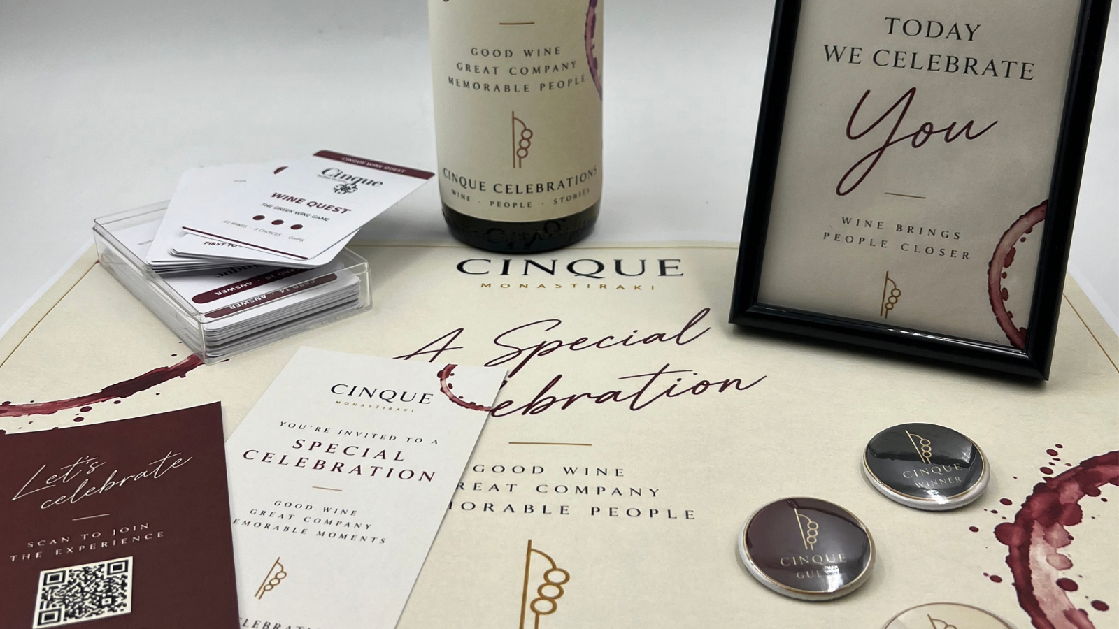 Cinque Celebrations setup at Monastiraki with Wine Quest cards, personalised bottle, pins and celebration frame