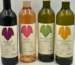 Four Cinque Essentials wine bottles: Merlot, Rosé, White Blend and Chardonnay, with coloured vine leaves and information on their labels.