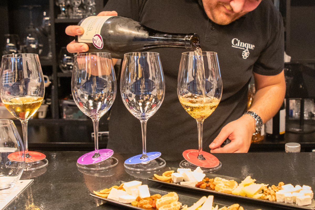 Nikitas Prassas pouring white wine beside tasting trays at Cinque