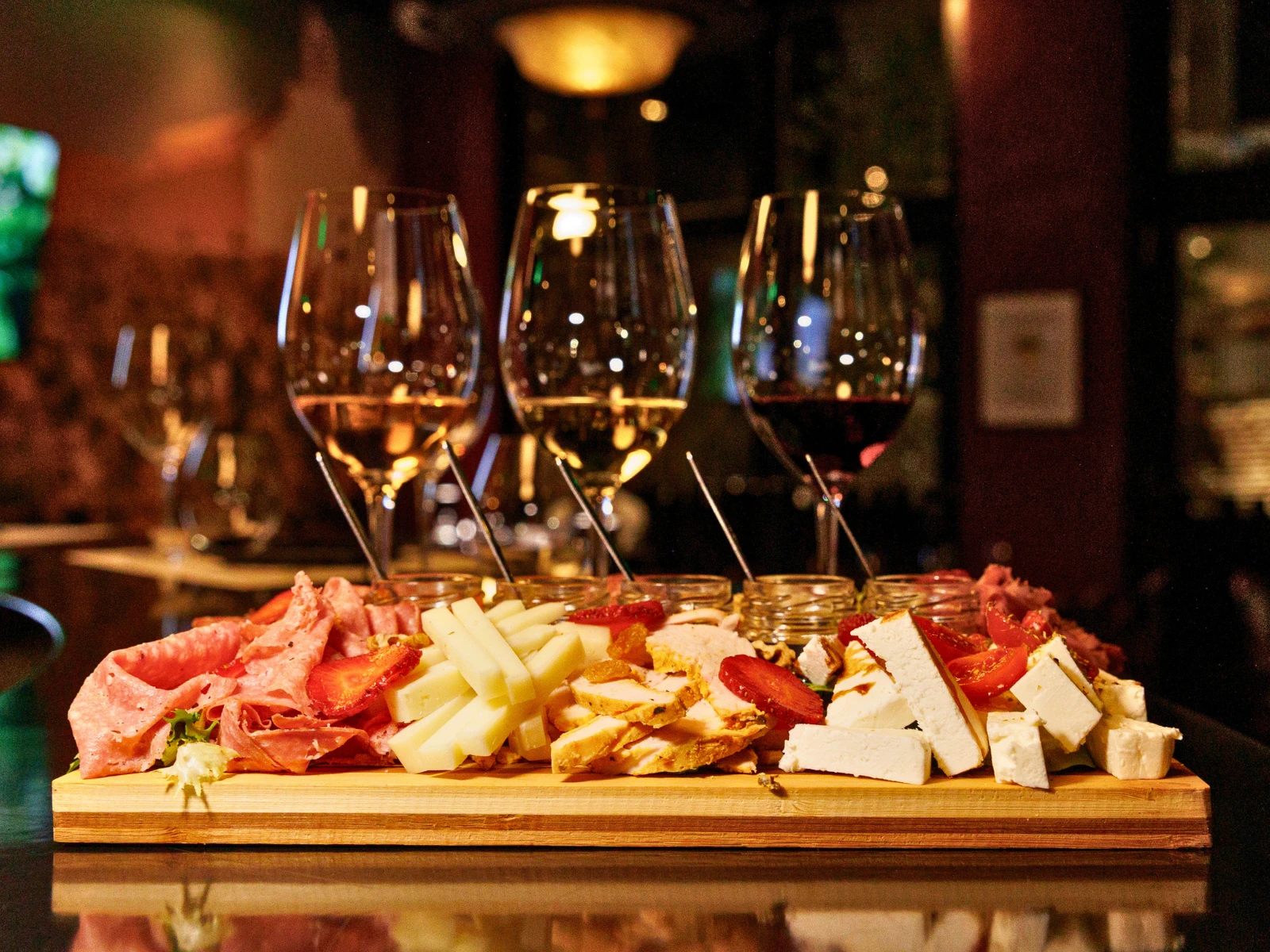 Three glasses of wine behind a cheese and charcuterie board at Cinque in Athens.
