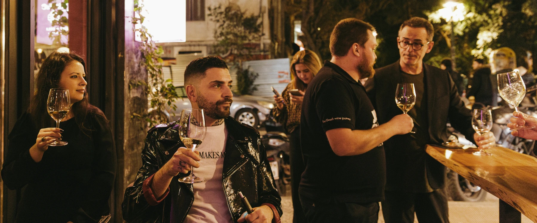 Guests enjoying wine and conversation outside Cinque Wine Bar in Athens.